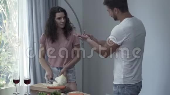 年轻的男人和女人在争吵而女人在割白菜女孩愤怒地把一把刀插在木板上视频的预览图