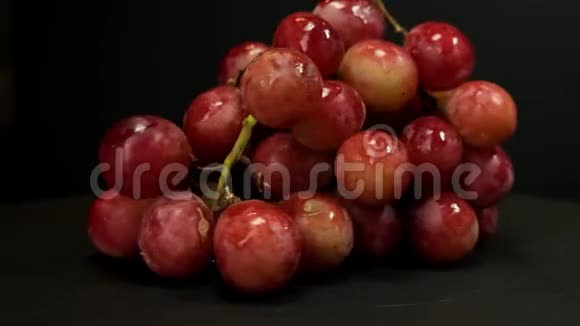 一串成熟的红葡萄在黑色背景上旋转快关门视频的预览图
