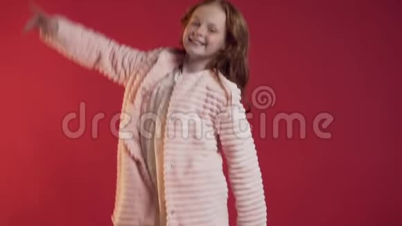 一个可爱的女孩在红色的背景上举起双手跳着笑得很开心视频的预览图
