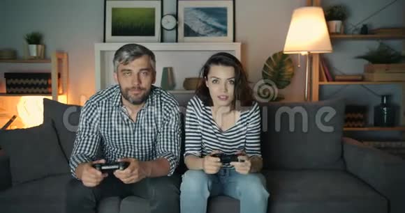 兴奋的男人和女人在黑暗的公寓玩电子游戏玩得开心视频的预览图