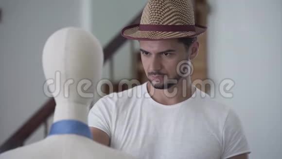 一个留胡子的人把帽子戴在人体模型的头上的肖像他在缝纫室玩得很开心视频的预览图