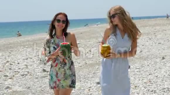 年轻漂亮快乐的女人手里拿着新鲜的水果鸡尾酒在海滩上跳着滑稽的舞蹈视频的预览图
