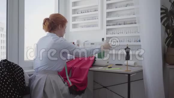 成功的可爱的红发女人在车间的桌子上缝纫裁缝工作勤奋细心业余爱好视频的预览图
