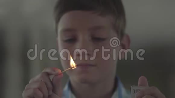 特写肖像可爱的小男孩在黑暗的烟雾弥漫的房间里玩火柴孩子笑着点燃火柴这就是视频的预览图