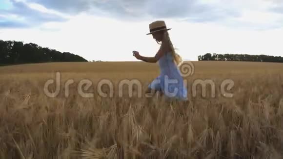 在阴天金发碧眼的美丽女孩在大麦草地上慢跑戴草帽的可爱快乐的孩子视频的预览图