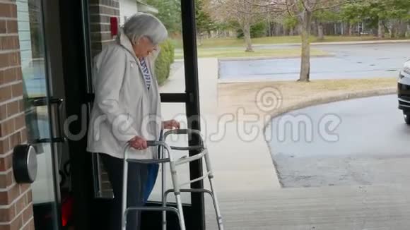穿着轻便夹克的老妇人在助行器的帮助下行走视频的预览图