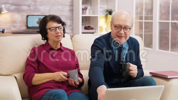 在视频通话中一对老年夫妇在笔记本电脑上挥手视频的预览图