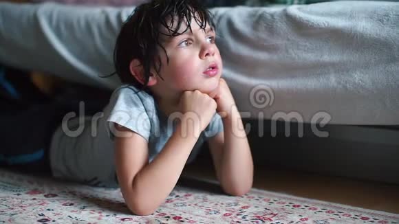 一个头发湿漉漉的小学生躺在他房间的地板上望着窗外视频的预览图