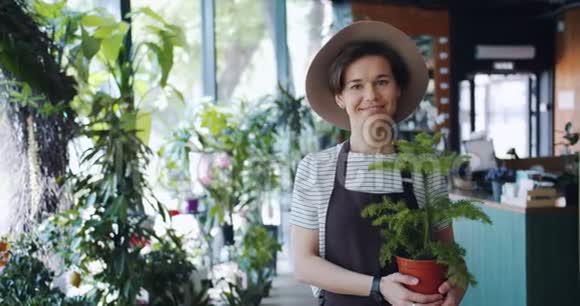花店里一位年轻可爱的女士拿着盆栽慢镜头画像视频的预览图