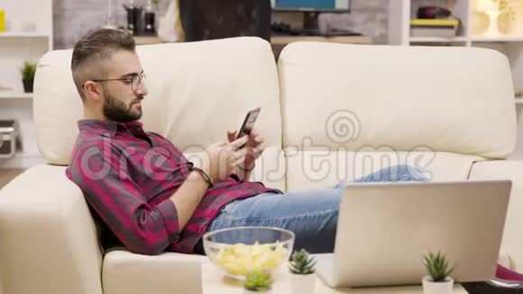 帅哥用手机在沙发上放松视频的预览图