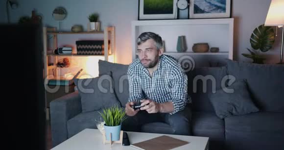 男人玩电子游戏嚼爆米花晚上享受休闲视频的预览图