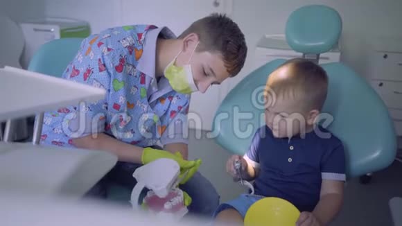 技能男孩医疗面具和手套和小孩在牙医办公室玩年轻人教孩子刷牙视频的预览图