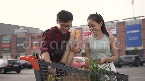 有趣的亚洲夫妇站在满是食物的市场手推车上互相开玩笑这幅画很有吸引力视频的预览图