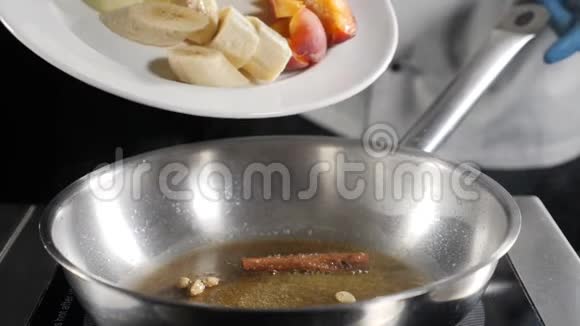 餐厅慢动作美食视频厨师把切片水果香蕉杏子放在煎锅上烹饪火焰式视频的预览图