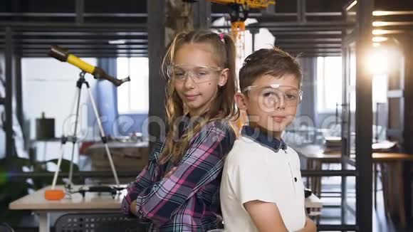 两个戴着安全护目镜的白人科学家孩子在小学化学中竖起大拇指的肖像视频的预览图