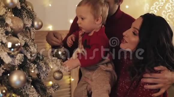 幸福的白种人家庭靠近圣诞树在舒适的家庭节日背景装饰圣诞树母亲抱着婴儿视频的预览图