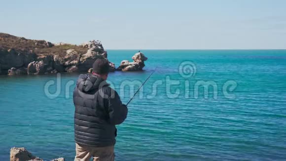 一个穿暖和衣服的渔夫在岩石中旋转着鱼视频的预览图