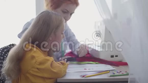 小女儿学习如何缝纫红头发的母亲向女孩展示如何选择衣服的纽扣视频的预览图
