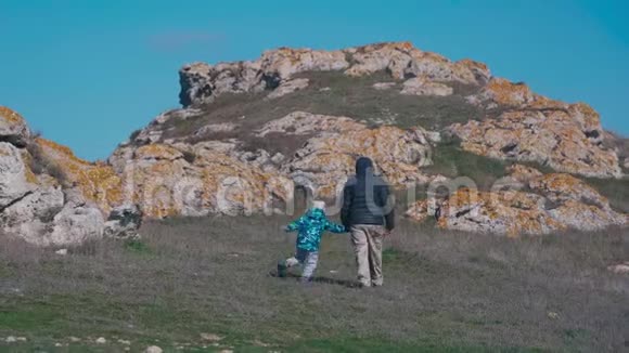 父亲和女儿穿着暖和的衣服走在克里米亚巨大的岩石中视频的预览图