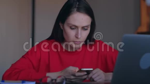 可爱的女人从笔记本电脑上覆盖智能手机信息视频的预览图