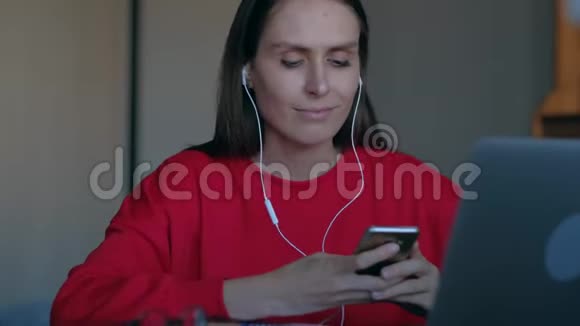 女性带着耳机听音乐坐在工作场所后面跳舞视频的预览图