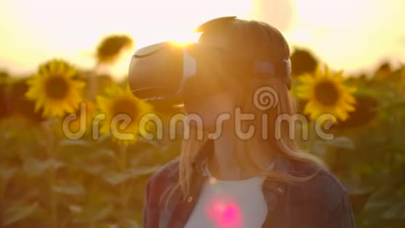 女孩正在花田日落时戴着VR眼镜工作视频的预览图
