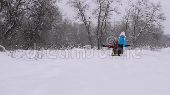 幸福童年的概念孩子和母亲在雪地里雪橇着他们的父亲女儿和妈妈在冬天和爸爸玩视频的预览图