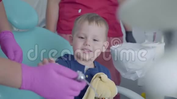 可爱的小男孩坐在牙医办公室的椅子上玩医疗工具免费儿童出诊医生视频的预览图