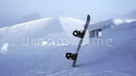 雪板站在雪地里在一个山脉的背景下陷在雪堆里白雪覆盖的冬天视频的预览图