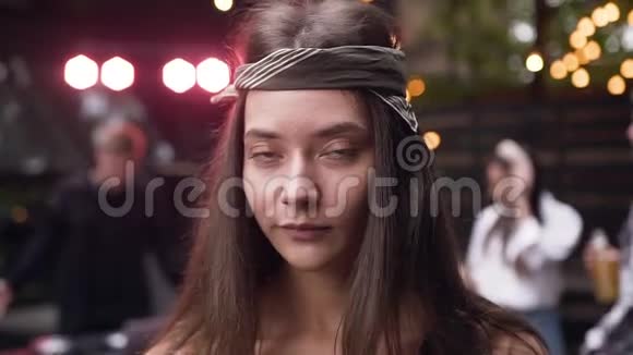 一个年轻漂亮的女人头上戴着头巾晚上在镜头前摆姿势视频的预览图