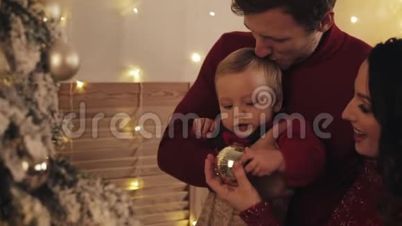 在家中爸爸妈妈和小儿子站在圣诞树旁宝宝和妈妈抱着视频的预览图