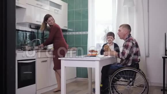 快乐的残疾父亲一边做饭一边和家人在厨房玩视频的预览图