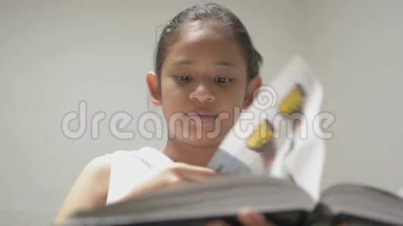 可爱的微笑的年轻女孩穿着白色衬衫在图书馆看书漂亮的女青少年喜欢搜索有用的信息视频的预览图