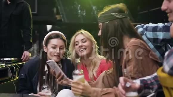 漂亮开朗的女人在手机上给坐在她身边的微笑的朋友看有趣的照片视频的预览图