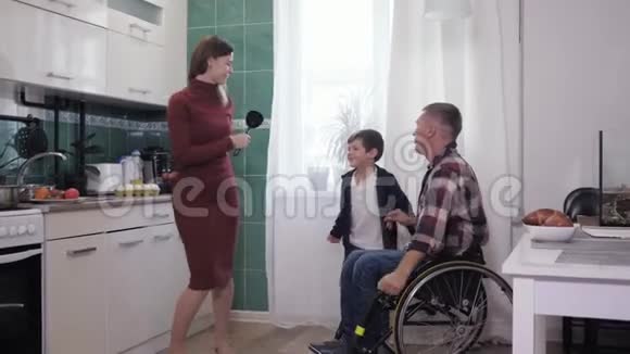 快乐的父亲残疾人和他的妻子和儿子在厨房里玩烹饪家庭关系视频的预览图