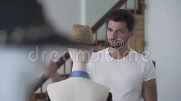 图为帅气的年轻胡子帅哥从人体模特身上摘下草帽戴上了头视频的预览图