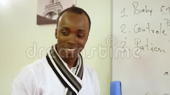 在白板附近戴着围巾和衬衫的黑人教师美丽的白牙笑脸的特写镜头视频的预览图