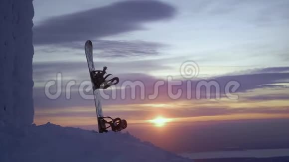 雪板站在雪地里困在夕阳背景下的雪堆里白雪覆盖的冬山视频的预览图