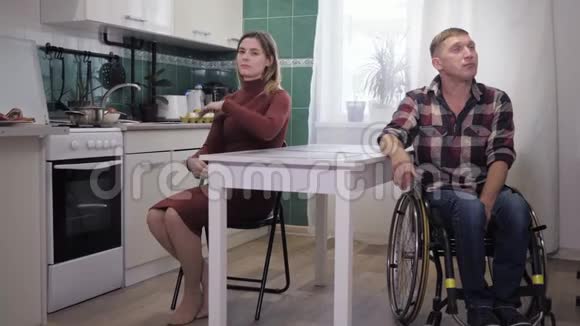 家庭争吵丈夫心烦意乱残疾人坐在轮椅上在厨房里和他固执悲伤的妻子咒骂视频的预览图