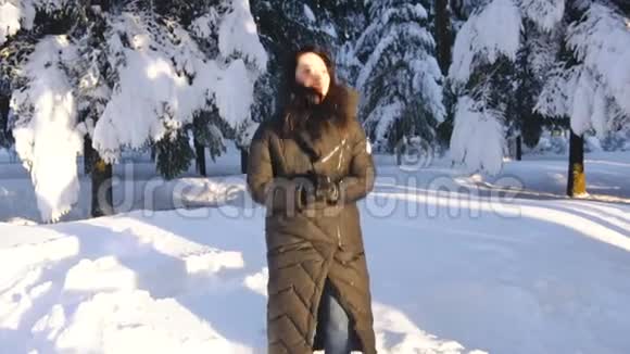 女孩在雪地里跳跃在森林里阳光明媚的冬日大笑视频的预览图