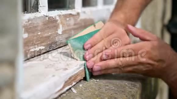 一个人他的手在打磨一个磨损的窗框视频的预览图