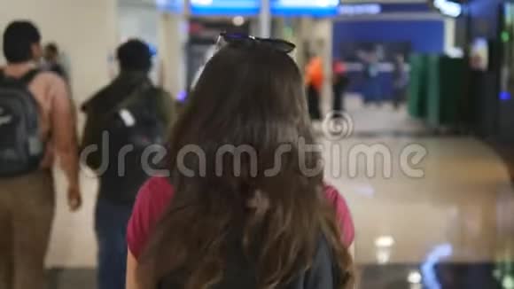 跟着年轻女孩沿着机场候机楼走穿过购物中心的女人背面视图视频的预览图