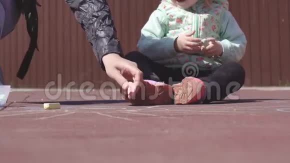 美丽的白种母亲带着3岁的小女儿在操场上用蜡笔画画游戏视频的预览图