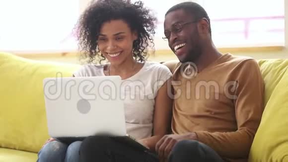 快乐的非洲年轻夫妇笑着在家用笔记本电脑说话视频的预览图