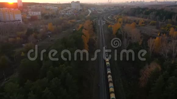 空中跟踪拍摄的日落时分通勤列车在秋林上行驶视频的预览图