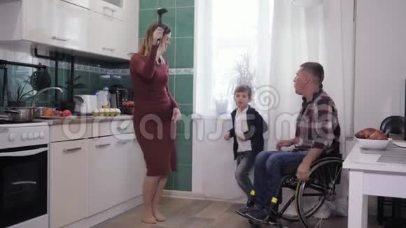 坐轮椅的男人和他的家人在厨房里玩得很开心在友好的气氛中跳舞和做饭视频的预览图