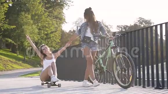 慢动作的迷人热情的女孩与自行车和滑板一起在城市小巷玩视频的预览图