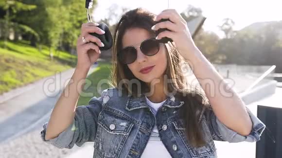 在城市背景下戴着耳机听音乐戴着墨镜长得好看的30岁老女人视频的预览图