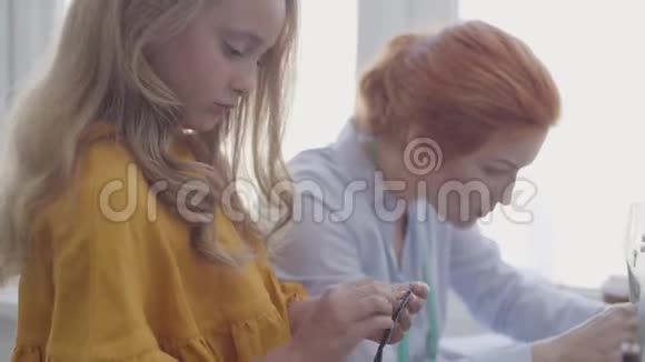 小女儿检查缝纫配件学习如何缝纫而她的红发母亲坐在视频的预览图