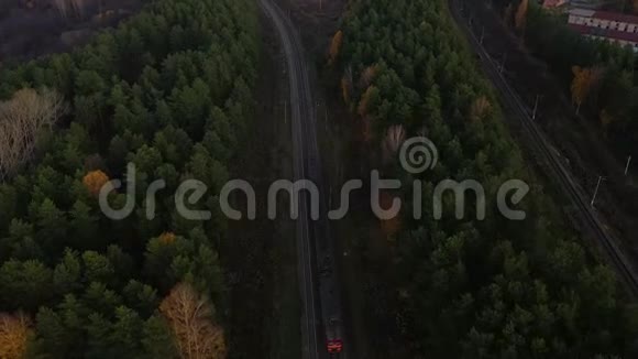日落时分在郊区火车通勤铁路上乘坐飞机穿过秋天的森林视频的预览图